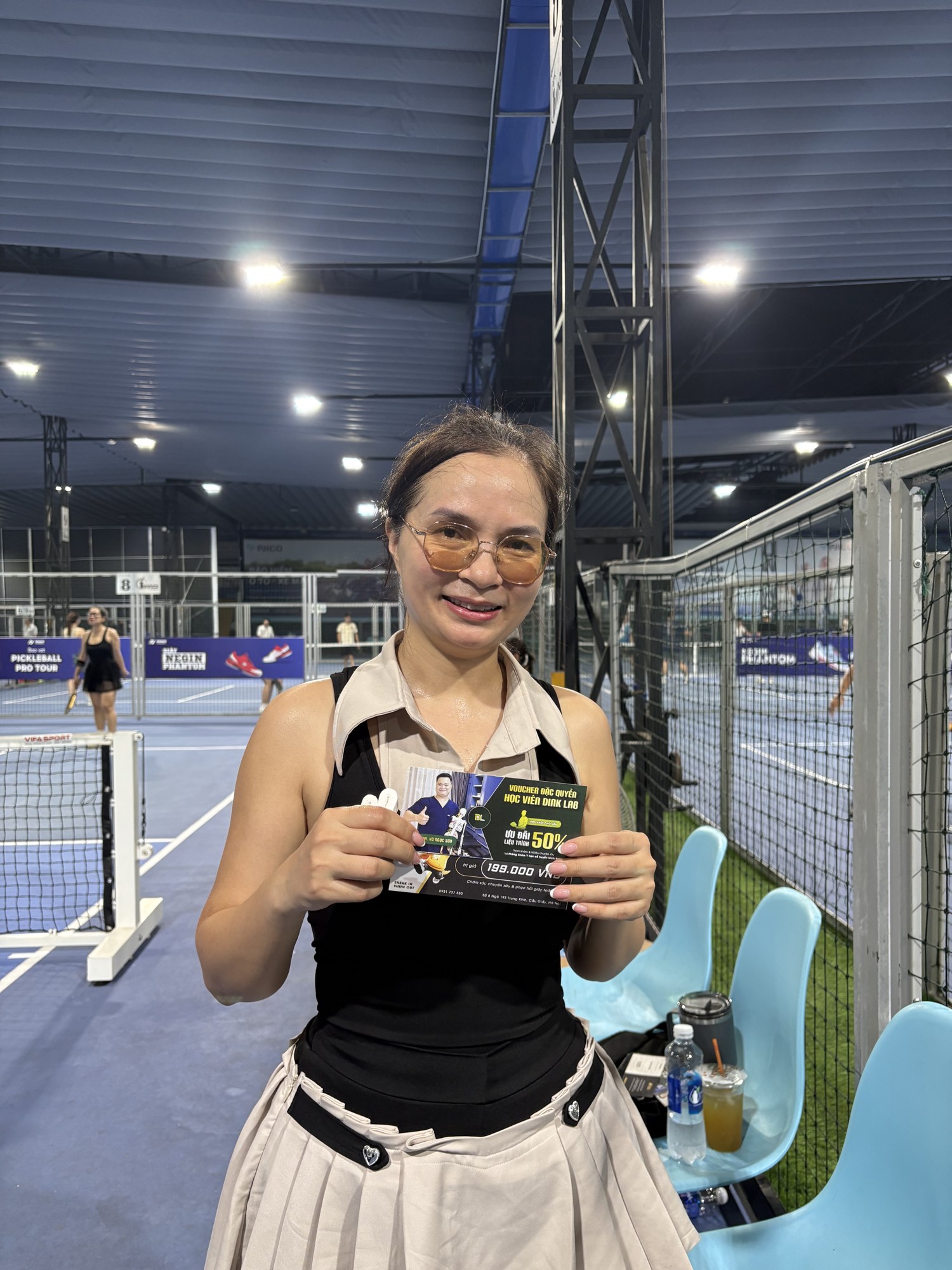 Người chơi nữ cầm voucher tri ân tại sân Pickleball Thượng Đình